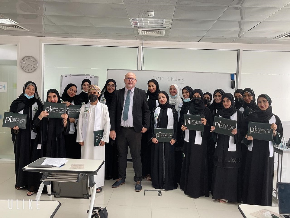 A class of teachers in Oman posing in a classroom holding their Cambridge English and IELTS certificates