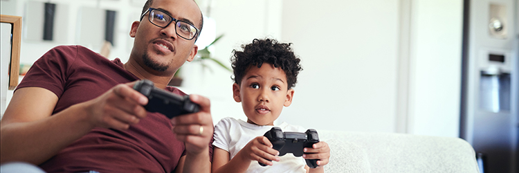 A dad and son each holding a video game controller and looking in the same direction