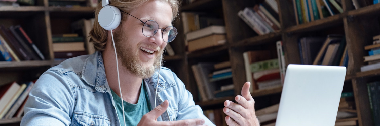 Student smiling and looking at a laptop while wearing headphones.