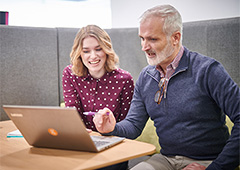 Male teacher working with female student on a laptop