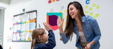 Teacher giving a high-five to a student in a classroom.