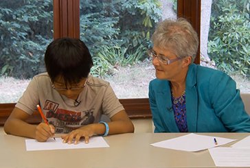 Adult helping a child to write in English