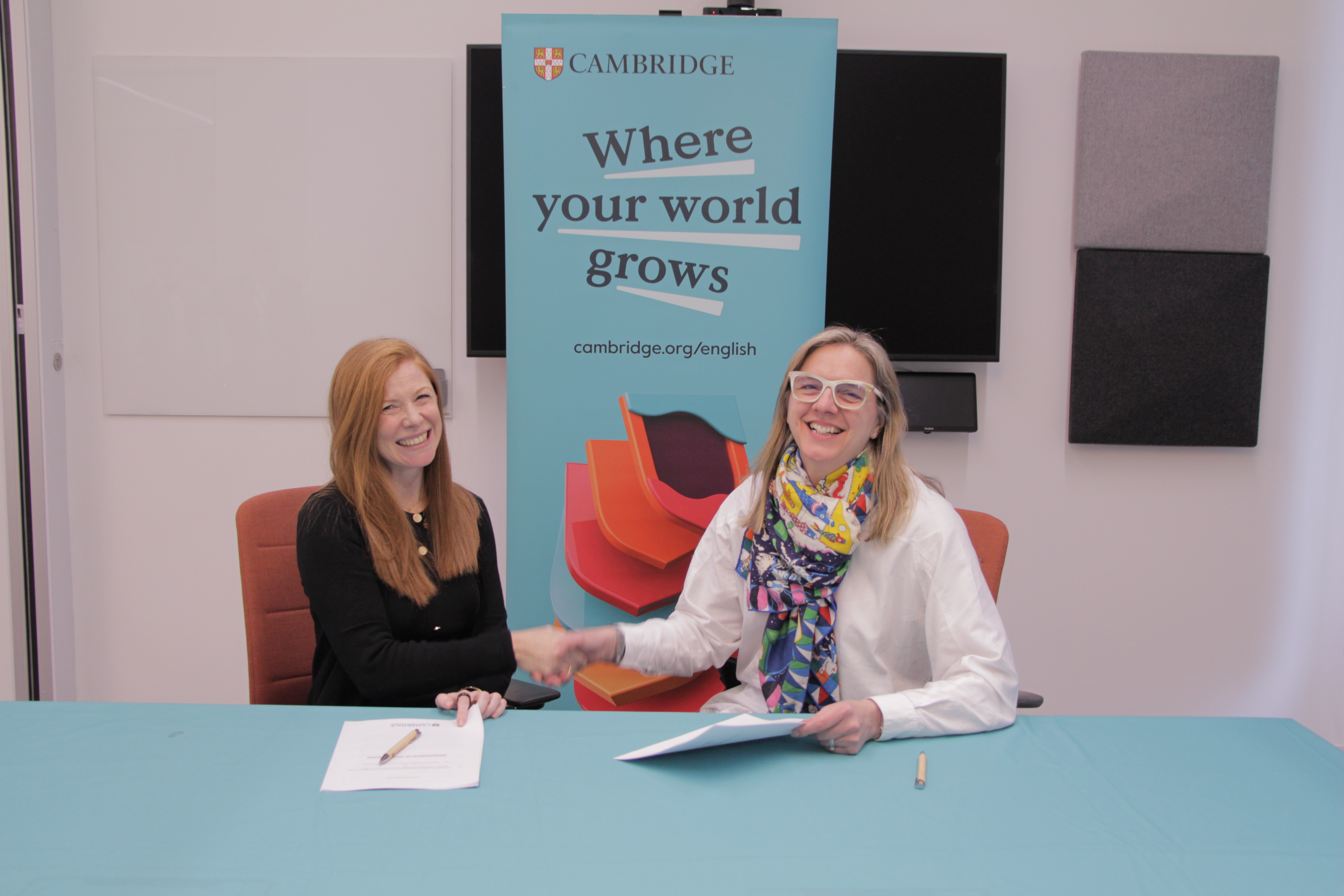 Two women shake hands at a Cambridge event.