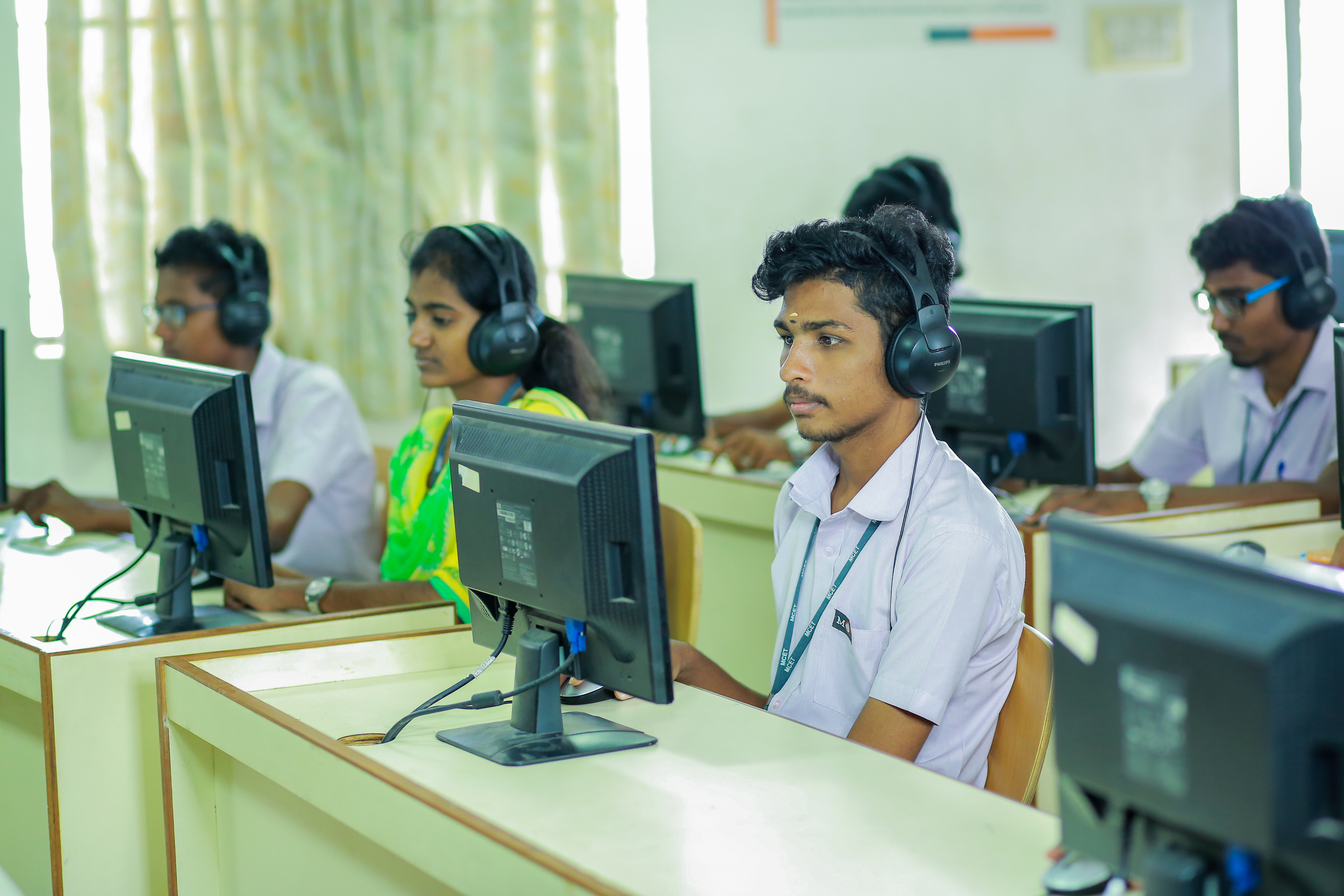 Students using desktop computers with headsets in a language lab.