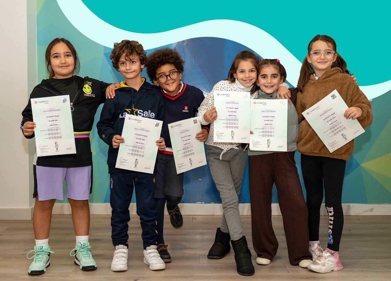 Group of young learners standing together and holding Cambridge certificates in front of a colorful wall.