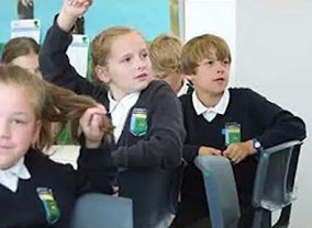 Students in a classroom raising hands.