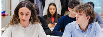 Students engaged in academic activity using smartphones in a classroom setting.