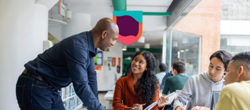 Teacher assisting students with a writing task.