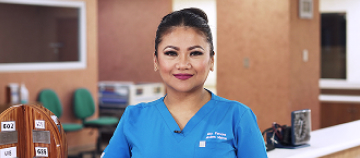 Woman in blue scrubs by a desk