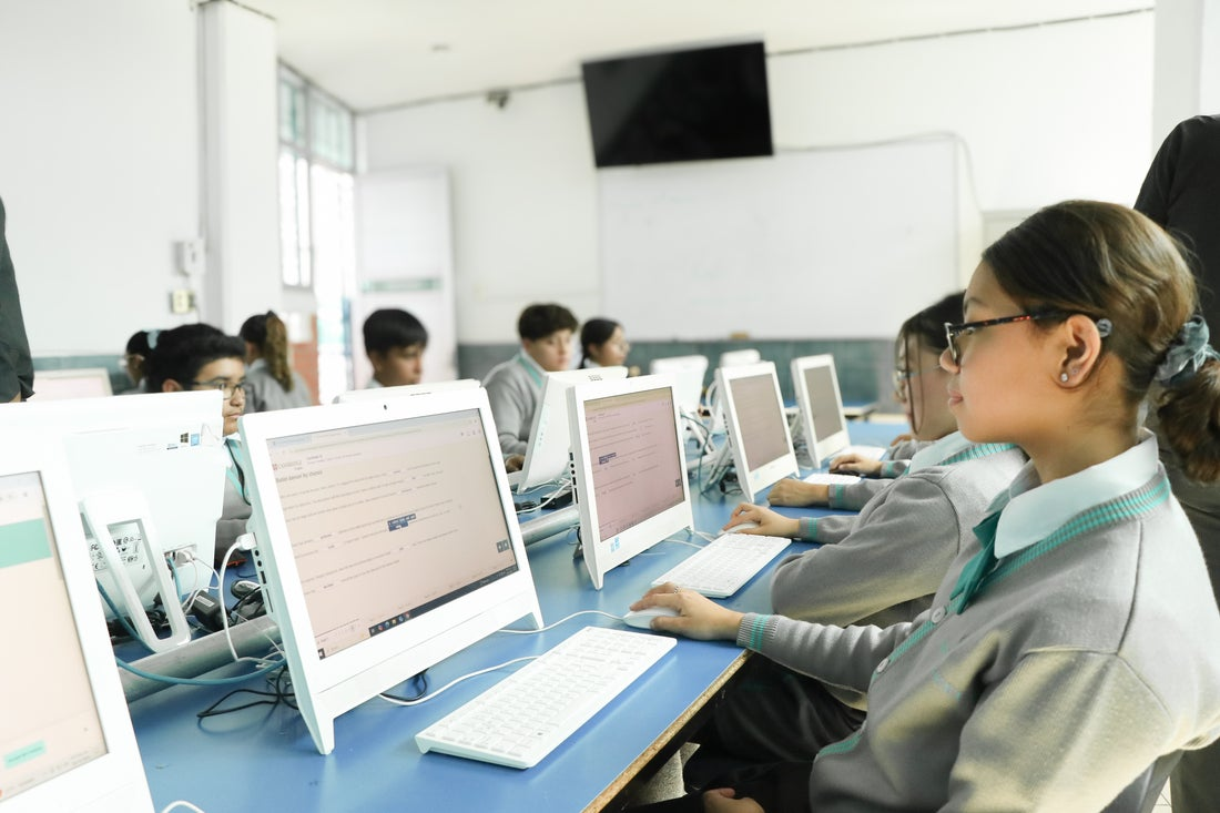 Students working on desktop computers in a classroom during a computer-based activity or exam.