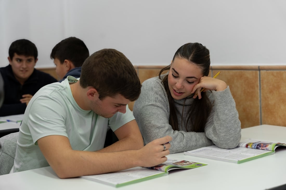 Students working together and reading from textbooks in a classroom.