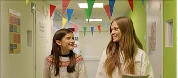 Students walking in a colorful school hallway holding books.