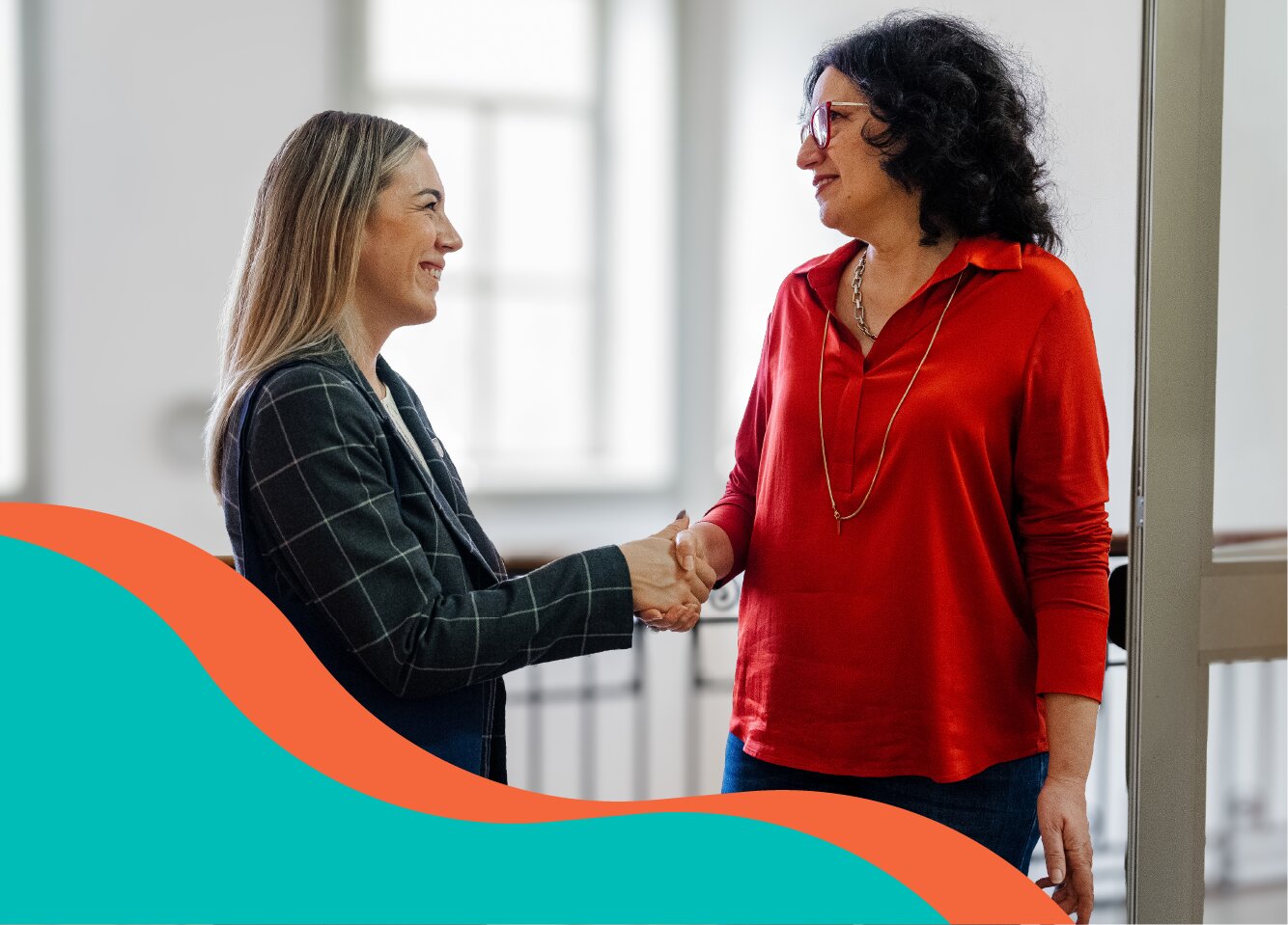 Two people shaking hands in a bright office setting.
