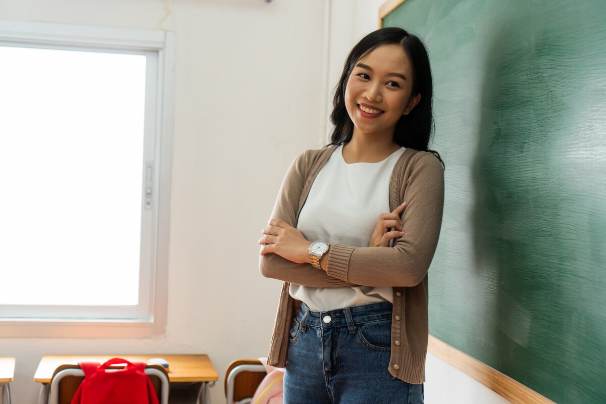 Person standing beside a classroom chalkboard.