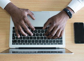Hands typing on a laptop keyboard.