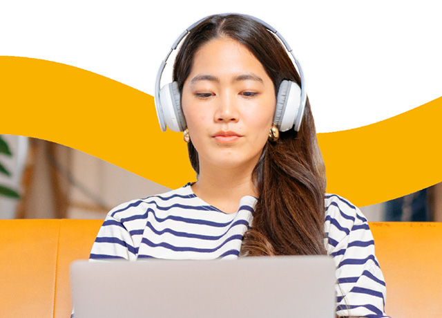 A Linguaskill test taker with headphones studying on a laptop