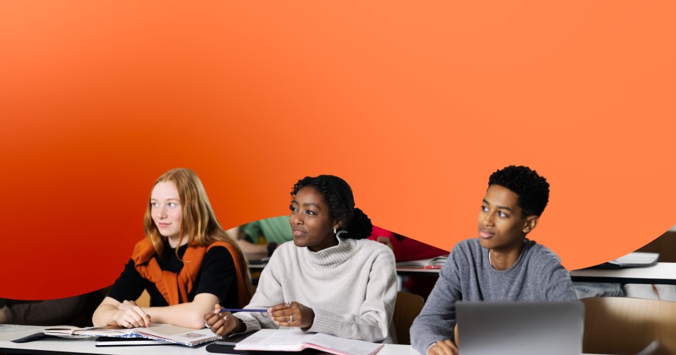 Étudiants apprenant sur des bureaux dans une salle de classe orange.