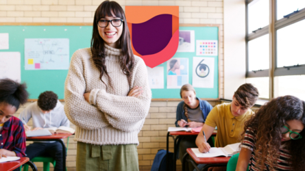 Professeur souriant debout devant des élèves travaillant en classe