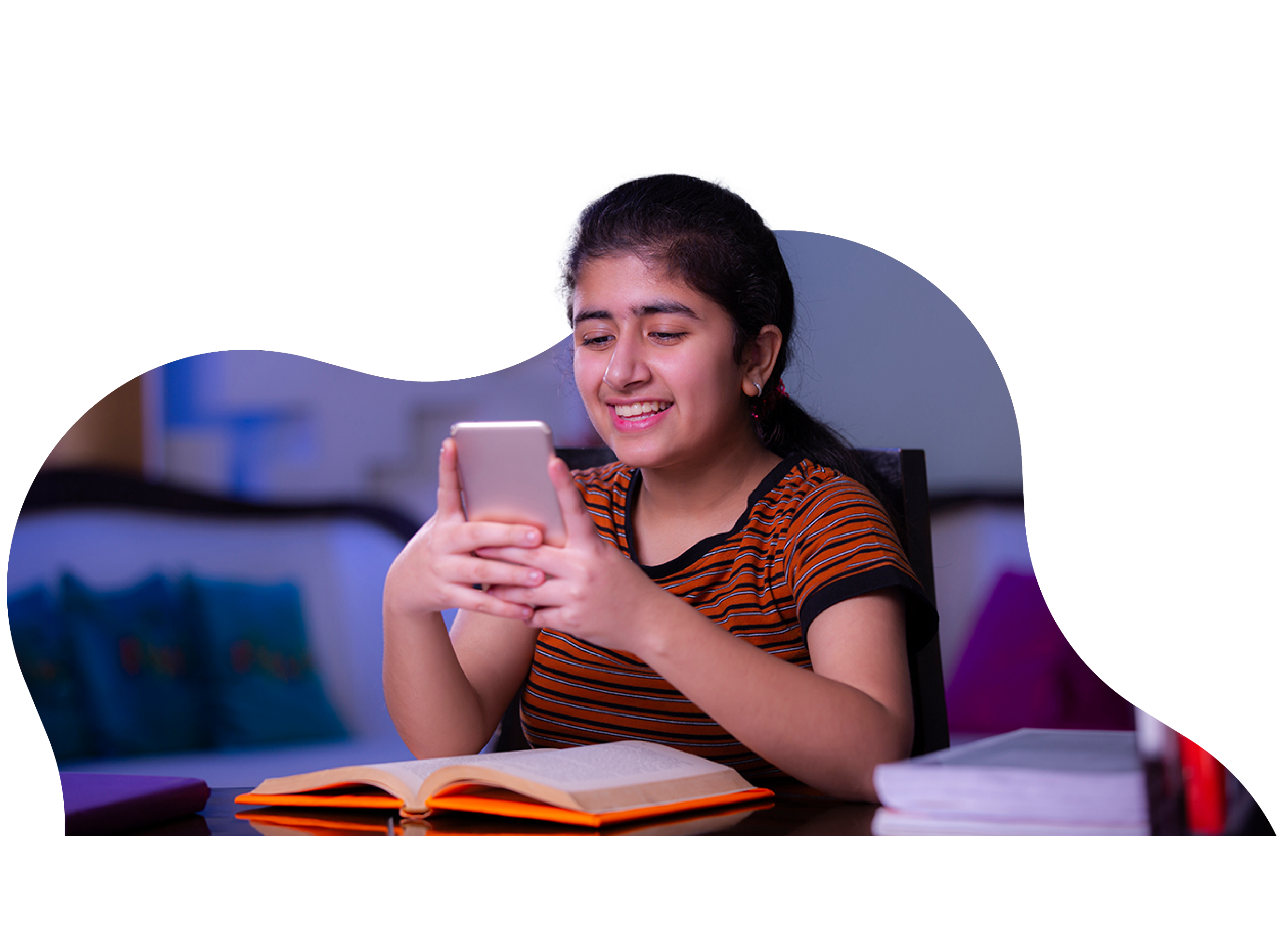 Girl using a mobile phone while studying at a desk.
