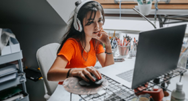 Una profesora concentrada que lleva auriculares y está sentada en un escritorio con su portátil.