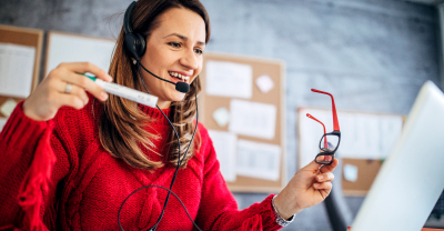 Una mujer con gafas y auriculares mira el portátil