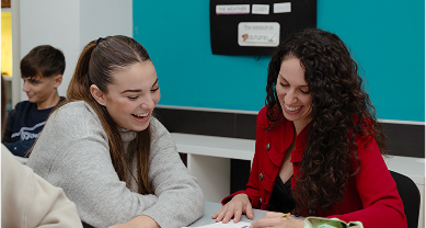 Dos mujeres jóvenes colaboran y sonríen