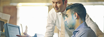 Two men discussing a document in English at work